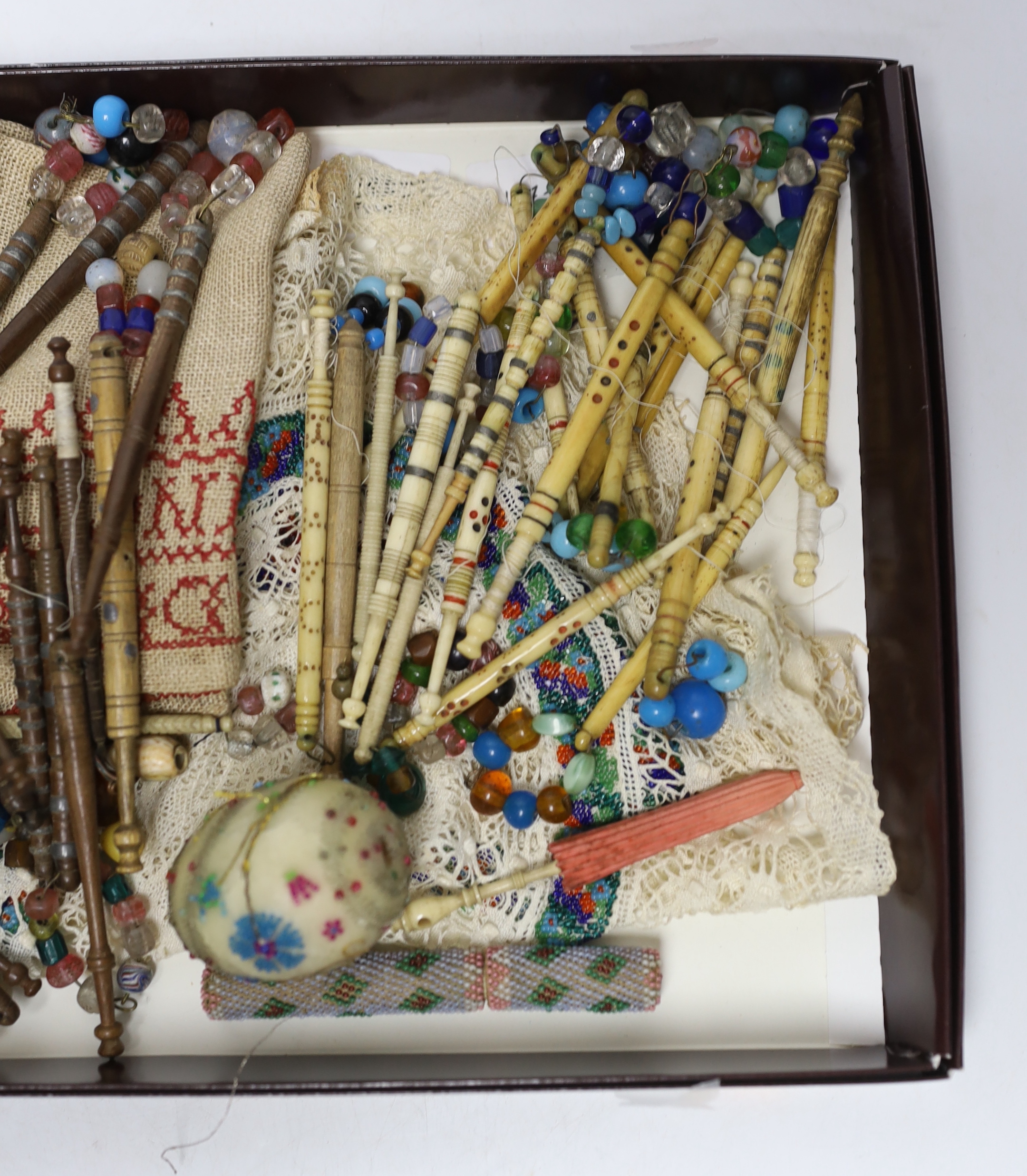 Sewing items: including a collection of bone and wooden lace maker’s bobbins, a beadworked needlecase, an egg and beadworked mats, etc.